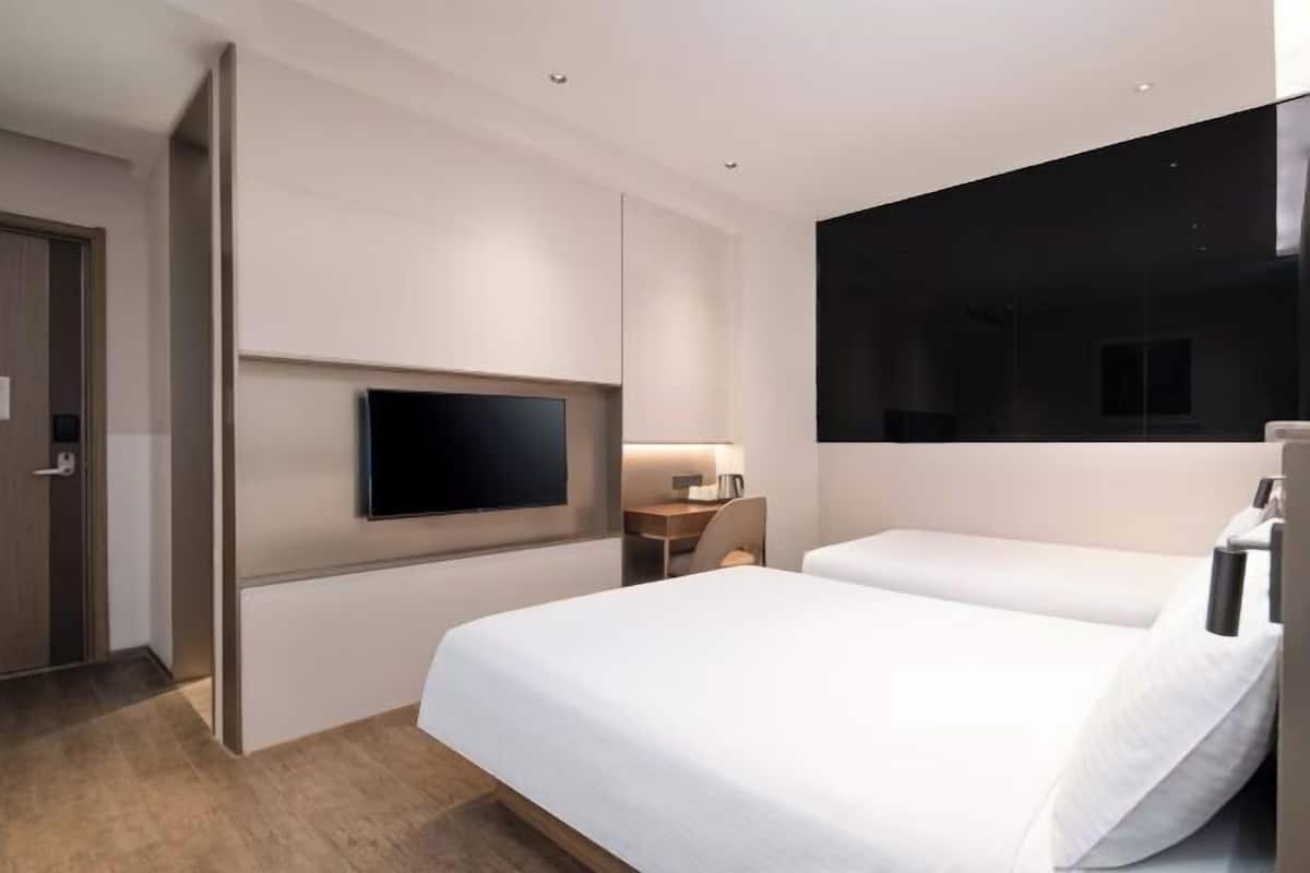A hotel room with a large bed, a desk, a chair, a flat-screen TV, and a large window.