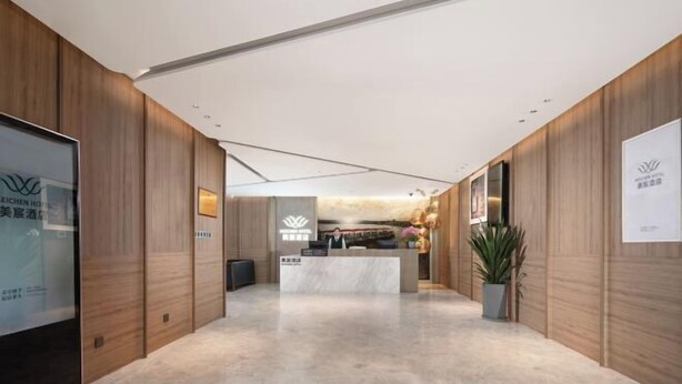 A hotel reception area with a reception desk, wooden paneling, and a potted plant. - MeiChen Hotel( within the terminal building of Beijing Daxing International Airport) (Beijing)