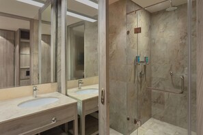 Une salle de bain moderne avec deux lavabos, une douche à l’italienne en verre et un grand miroir.