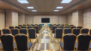 A conference room with rows of chairs, a large screen, and a patterned carpet. - Aloft Kathmandu Thamel (Kathmandu)