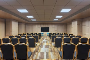 A conference room with rows of chairs, a large screen, and a patterned carpet. - Aloft Kathmandu Thamel (Kathmandu)