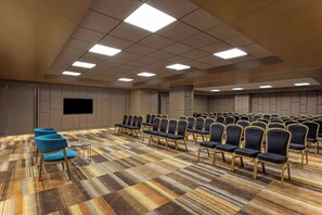A conference room with rows of chairs, a large screen, and a patterned carpet. - Aloft Kathmandu Thamel (Kathmandu)