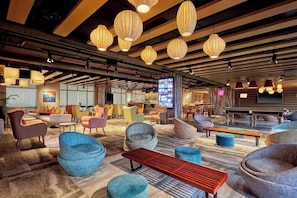 Un vestíbulo espacioso con asientos modernos, un banco de madera e iluminación colgante.