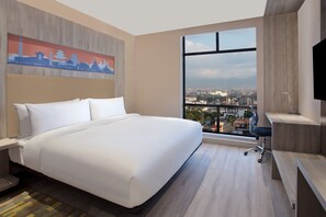 Une chambre d’hôtel avec un grand lit, un bureau, une chaise, une télévision et une vue sur la ville.