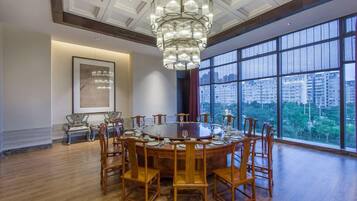 Uma sala de jantar com uma mesa redonda, cadeiras e um lustre.