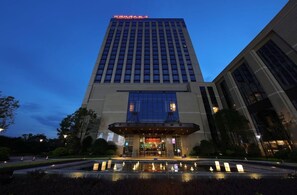 A modern hotel building with a prominent entrance and a reflective water feature in front. - Amitabha Hotel (Fuzhou)