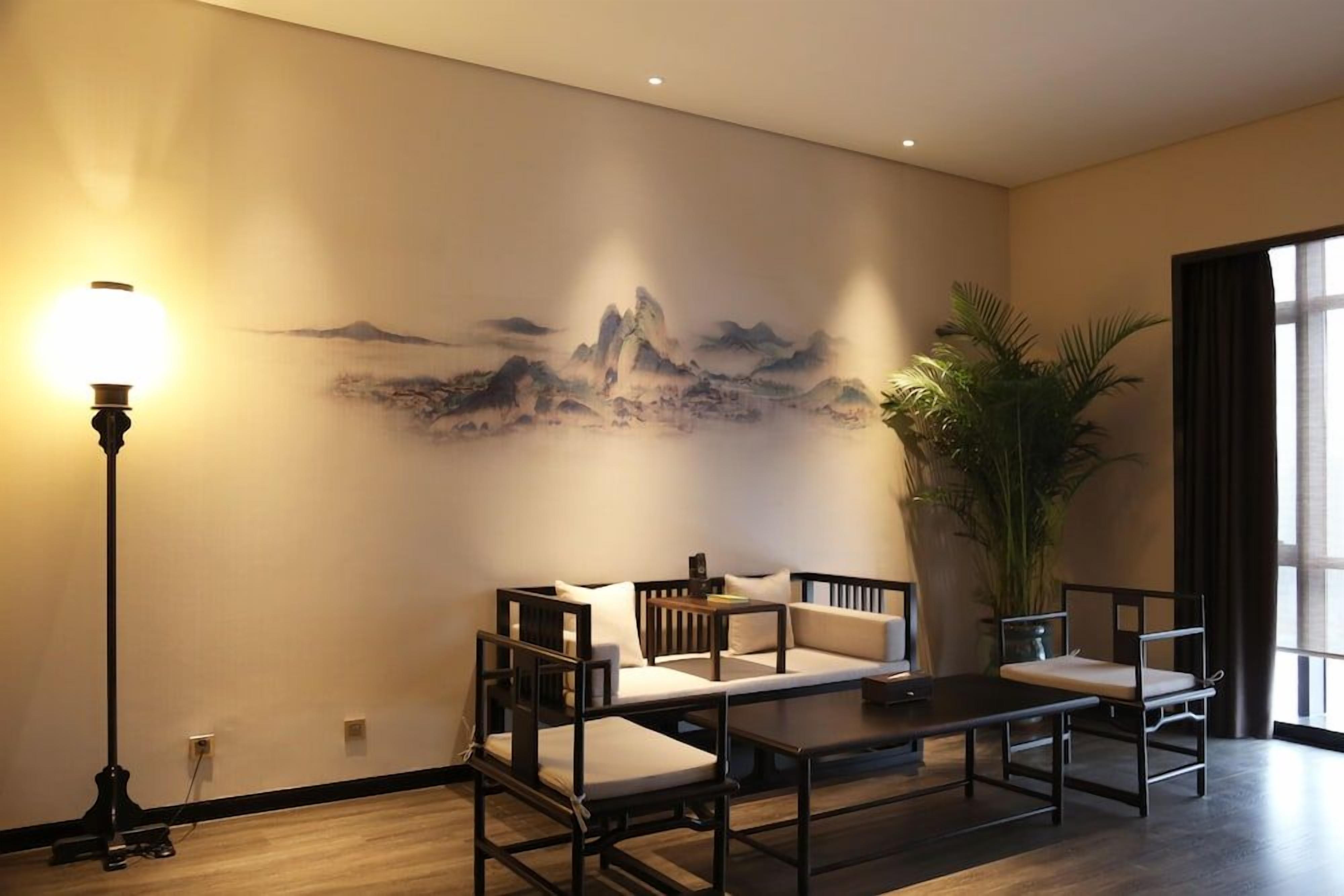 Quarto com sofá, mesa, luminária e uma grande pintura na parede.
