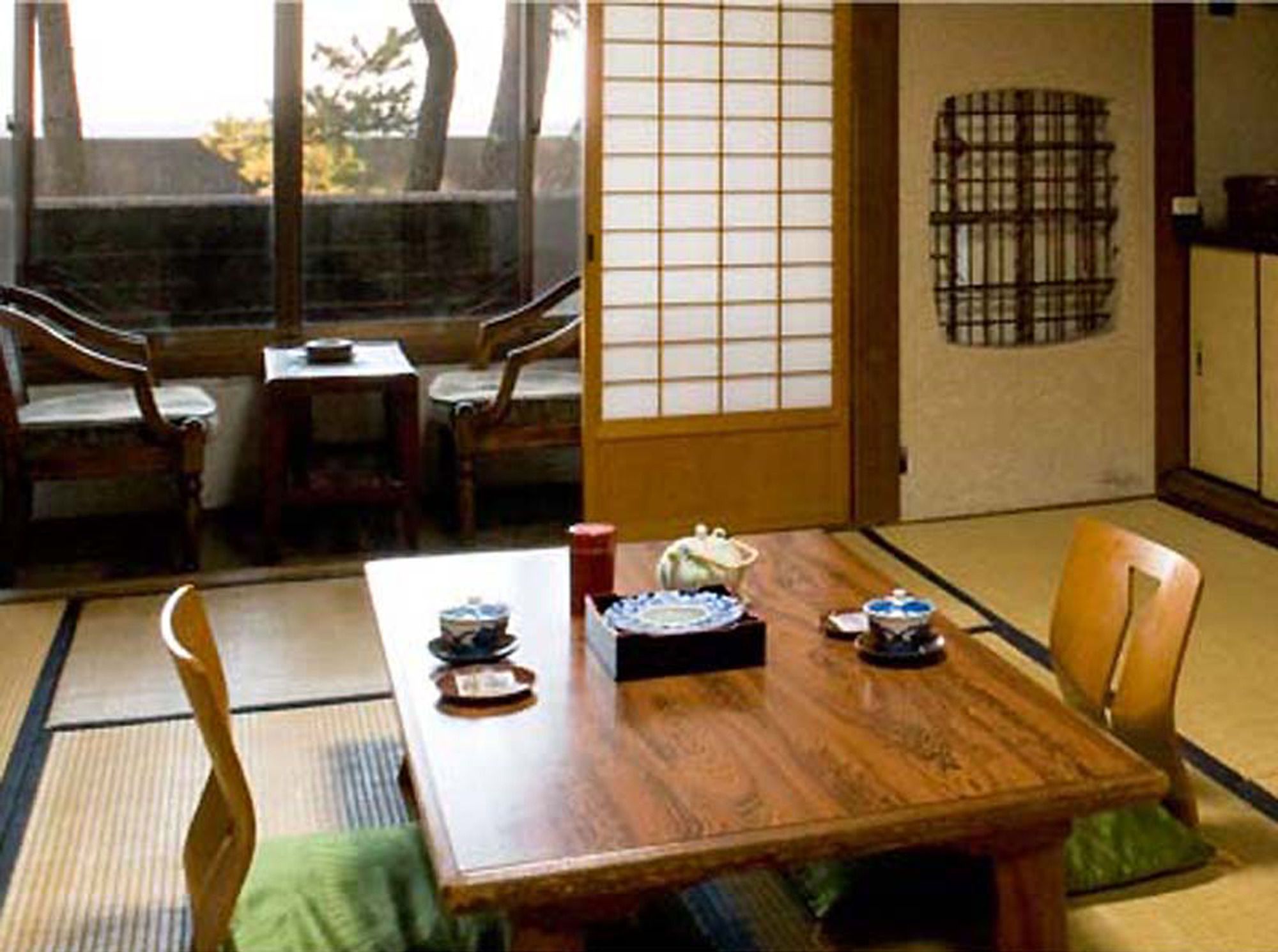 Una habitación japonesa tradicional con suelo de tatami, una mesa baja con un juego de té y puertas correderas.