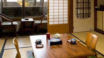 Una habitación japonesa tradicional con suelo de tatami, una mesa baja con un juego de té y puertas correderas.