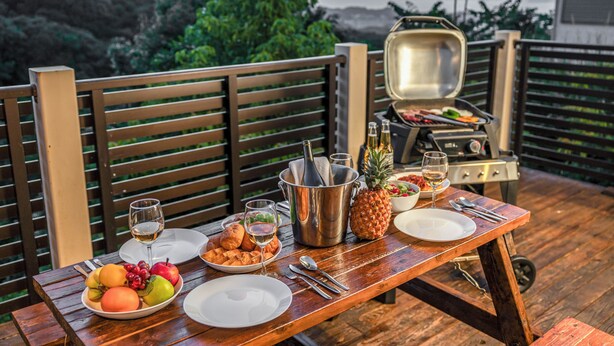 An outdoor dining setup with a grill, a wooden table, and a scenic view of hills and trees. - Hopehills Hiramatsutei (Shirahama)