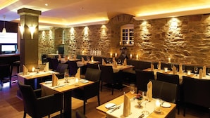 Ein Restaurant mit Stehwänden, Holztischen und -stühlen, und einem Fernseher im Hintergrund.