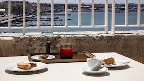 A table with food and drinks on a balcony overlooking a marina with boats and buildings. - Dogana Resort (Molfetta)