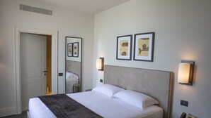 A hotel room with a large bed, a bedside table with a phone, and two wall-mounted lamps. - Dogana Resort (Molfetta)
