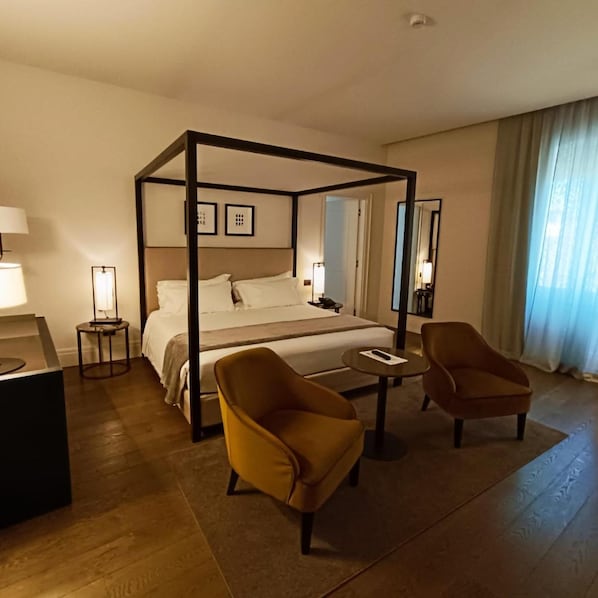 A four-poster bed with a nightstand, two armchairs, a small table, and a mirror. - Dogana Resort (Molfetta)