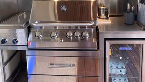 Une cuisine en acier inoxydable équipée d’un four encastré, d’une plaque de cuisson et d’un réfrigérateur.