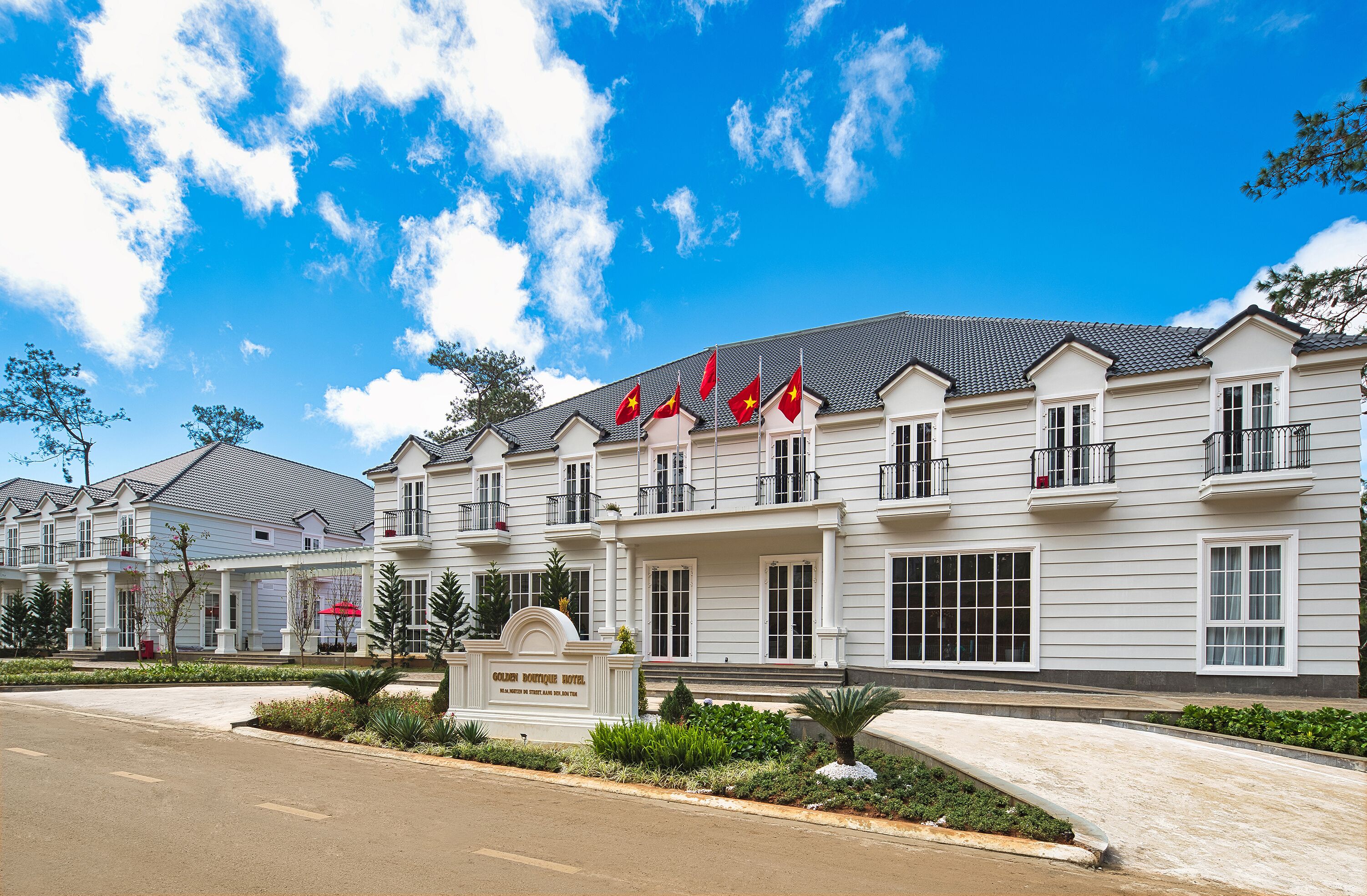 A hotel with a white facade, multiple flags, and a sign indicating it is the Golden Boutique Hotel.