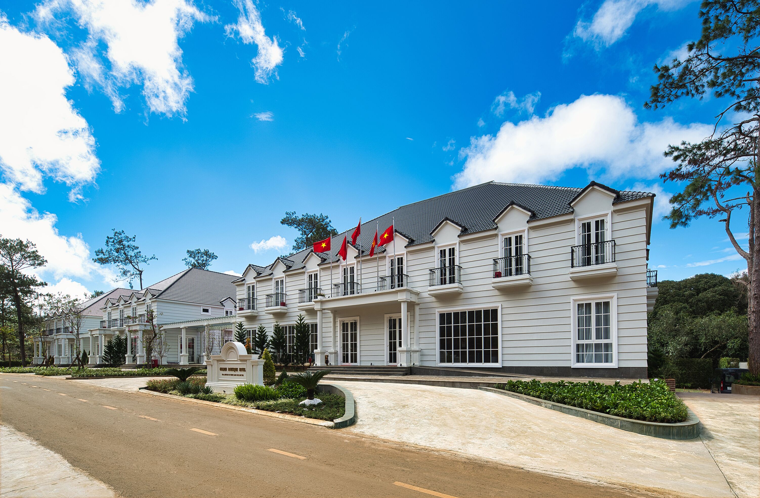 A multi-story hotel with a symmetrical facade, multiple balconies, and a well-maintained driveway.