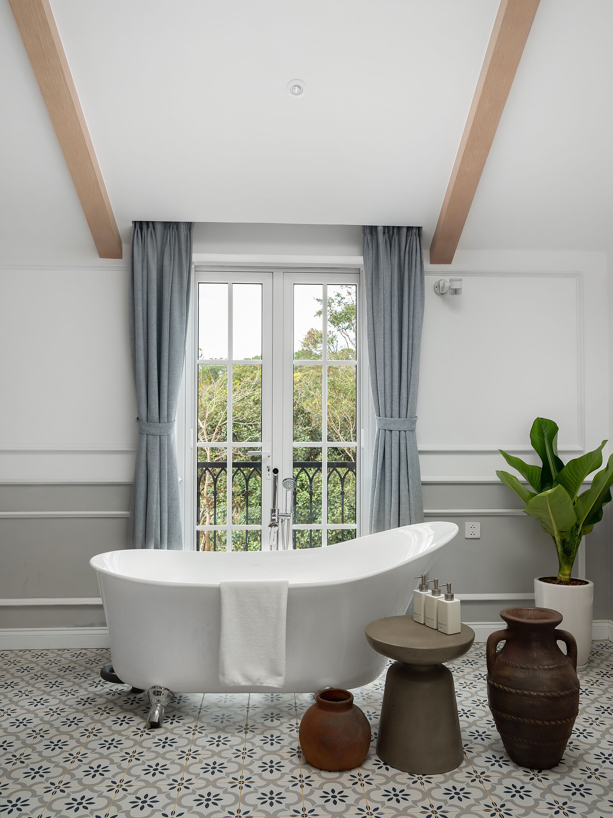 Un baño moderno con una bañera independiente, una planta en maceta y un jarrón decorativo.