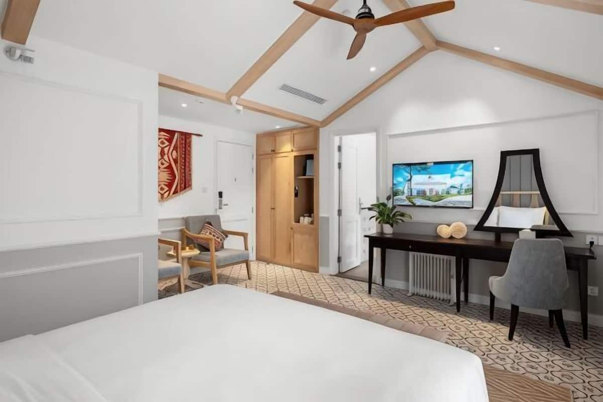 Un dormitorio con cama, escritorio, silla, televisor y armario.