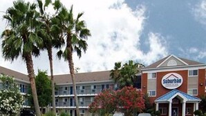 A Suburban hotel with a brick facade, multiple floors, and a blue roof. - Suburban Studios Stuart Near Federal Hwy 1 (Stuart)
