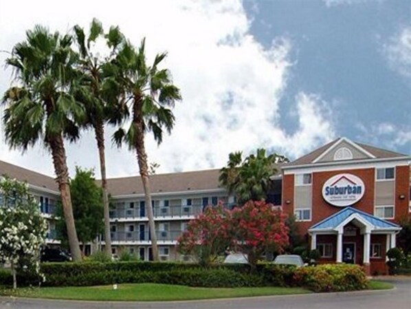 A Suburban hotel with a brick facade, multiple floors, and a blue roof. - Suburban Studios Stuart Near Federal Hwy 1 (Stuart)