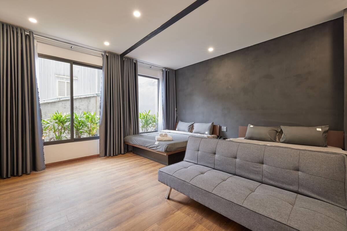 A modern bedroom with a sofa, a bed, and a large window with curtains.