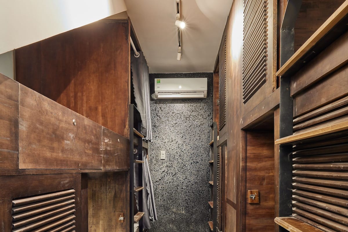 A narrow hallway with bunk beds on either side, a ceiling light, and an air conditioning unit.