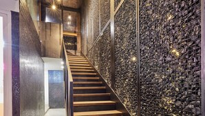 A staircase with wooden steps and a wall of small, reflective panels. - The Garden Capsule Hotel (Da Nang)
