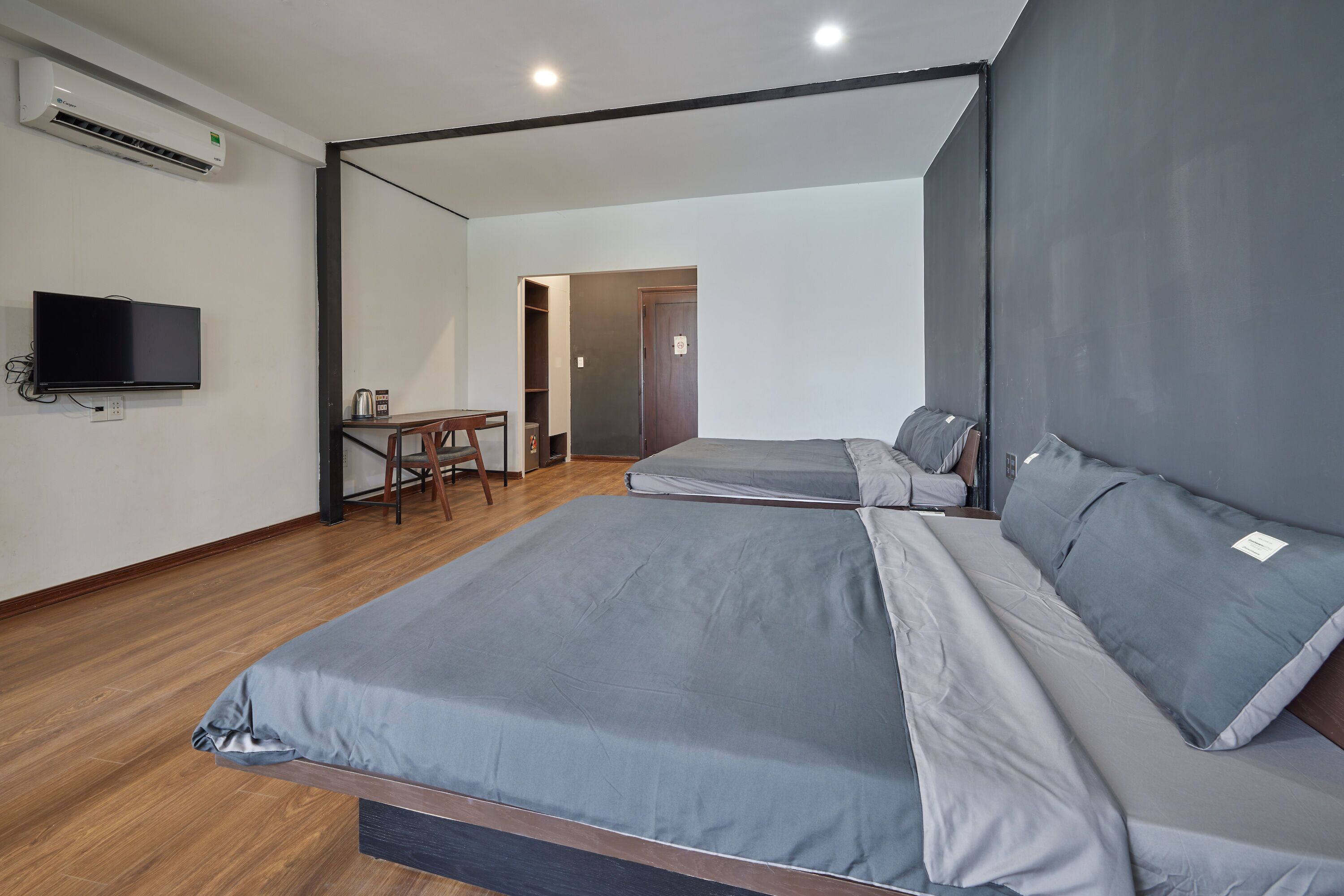 A modern room with two beds, a desk, and a television.