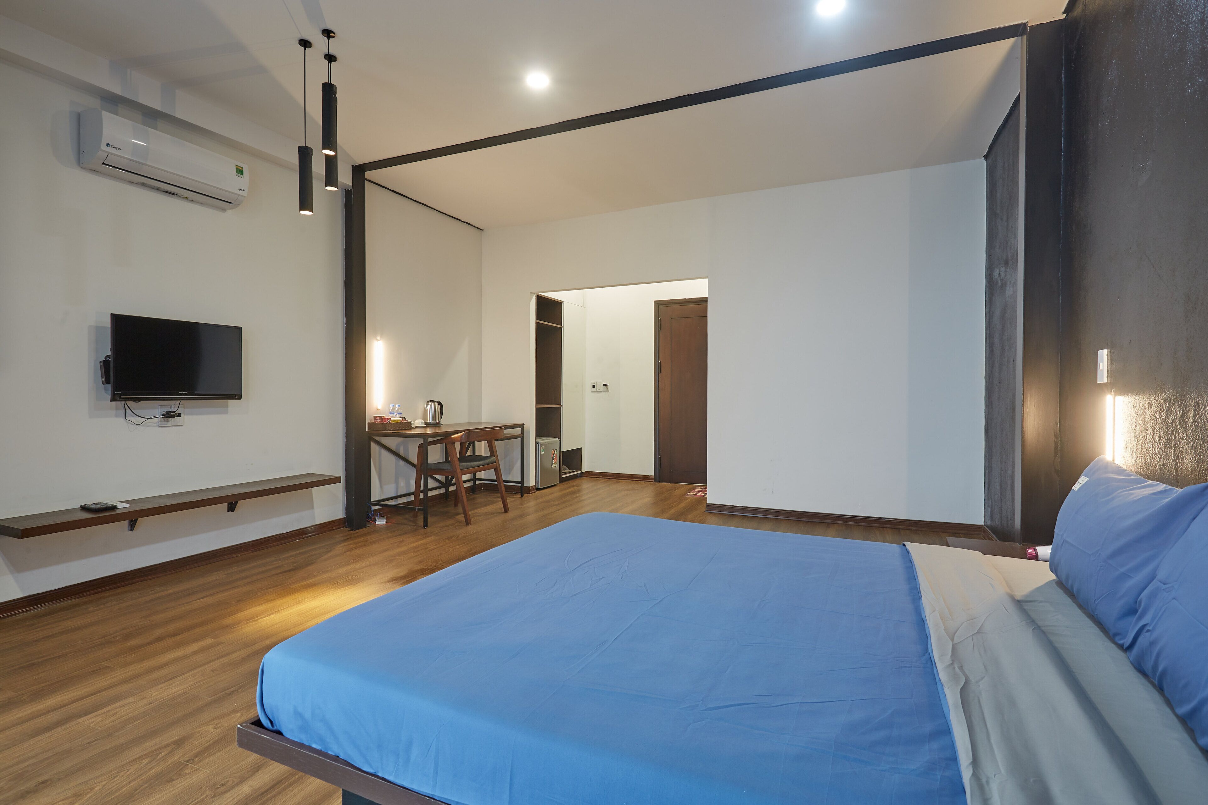 A modern bedroom with a large bed, a desk, and a television.