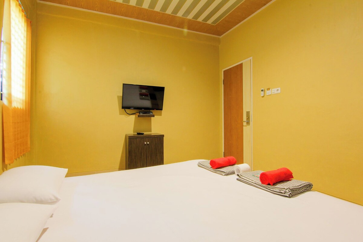 A hotel room with a bed, a television, a wooden cabinet, and a door.