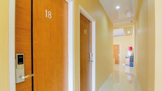 A hallway with wooden doors numbered 17 and 18, leading to a kitchen area with a water dispenser. - Yani Homestay by Zuzu (Padang)