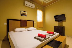 A hotel room with a bed, a TV, and an air conditioner. - Yani Homestay by Zuzu (Padang)