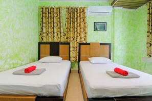 A room with two beds, a curtain, an air conditioning unit, and a framed picture on the wall. - Yani Homestay by Zuzu (Padang)