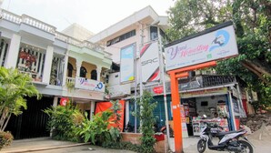 A building with a storefront, a sign for 'Yoni Homestay Backpacker,' and a parked motorcycle. - Yani Homestay by Zuzu (Padang)
