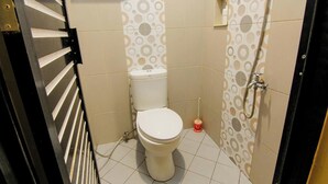A small bathroom with a toilet, a shower, and a hand dryer. - Yani Homestay by Zuzu (Padang)