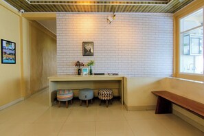 Un área de recepción con pared de ladrillo blanco, un letrero de Wi-Fi, un banco y tres taburetes estampados.