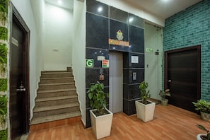 A staircase leading to an elevator, a door marked 'EXIT,' and potted plants. - Hotel Sky View (New Delhi)