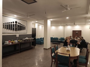 Un salón de conferencias con una mesa redonda, sillas y una zona de bufé con alimentos.