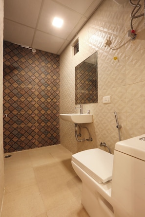 Un baño con pared con diseño, un lavabo, un espejo y un inodoro.