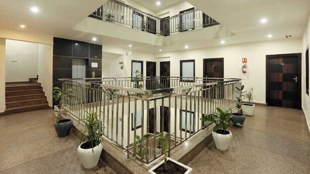 Un espace intérieur à plusieurs niveaux, doté d’un escalier central, de plantes en pot et d’une rambarde en métal.