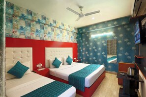 A hotel room with two beds, a ceiling fan, a TV, and a mirror. - Hotel Sky View (New Delhi)