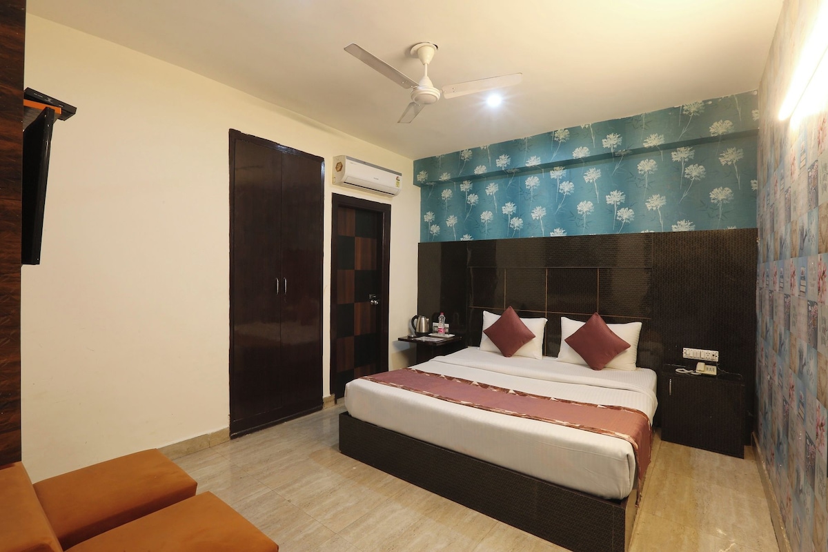Habitación de hotel con cama, mesita de noche, escritorio, armario y ventilador de techo.