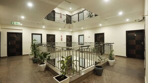 Un atrium à plusieurs niveaux, doté d’un escalier central, de plantes en pot et d’un panneau indiquant la sortie de secours en cas d’incendie.