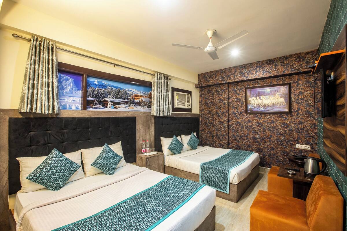 A hotel room with two beds, a ceiling fan, a mounted TV, and a coffee machine.