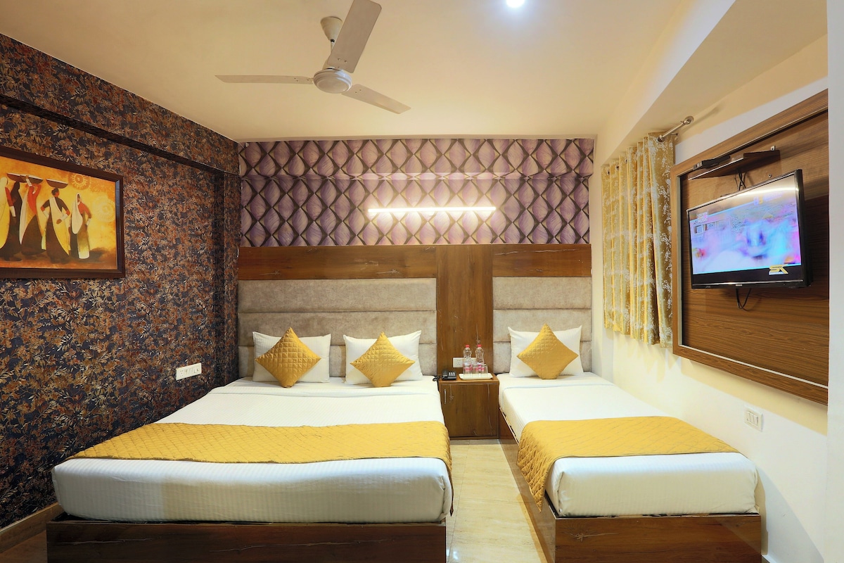 Habitación de hotel con dos camas, ventilador de techo, televisor y pared con diseño.
