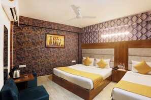 A hotel room with a large bed, a smaller bed, a desk with a kettle, and a painting on the wall. - Hotel Sky View (New Delhi)