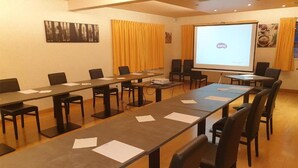 Una sala de conferencias con una mesa larga, sillas, una pantalla de proyector y una presentación en ella.