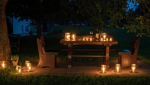 An outdoor dining area with a wooden table and chairs, surrounded by candles. - Hotel Sonnenhof (Neuweiler)