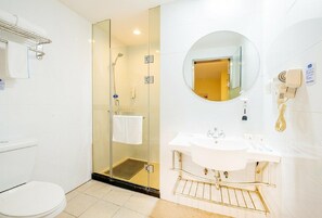 A modern bathroom with a glass-enclosed shower, a white sink with a gold faucet, and a round mirror.